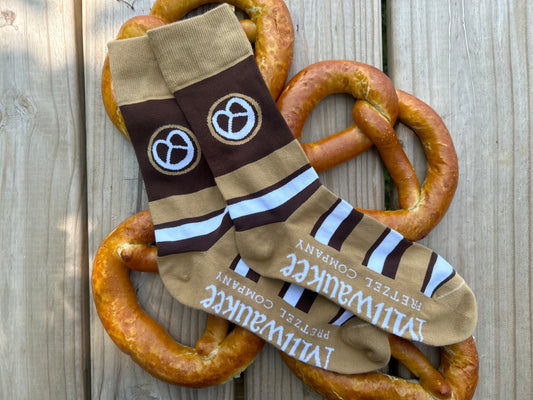 Brown, white and tan Milwaukee Pretzel Company socks that feature a pretzel graphic and the Milwaukee Pretzel Company logo