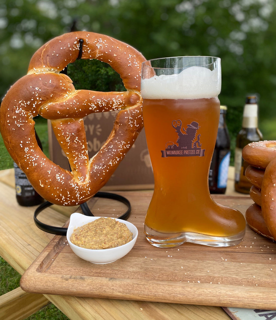 Milwaukee Pretzel Company boot beer glass next to a pretzel twist and mustard in a serving dish