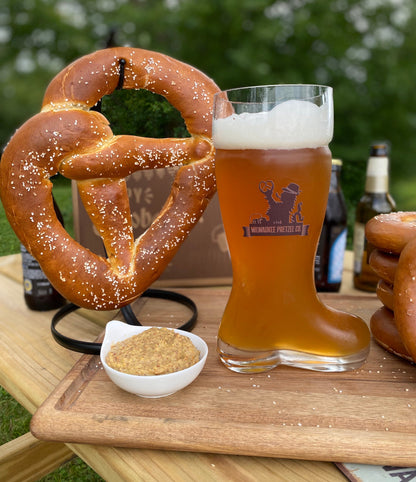 Milwaukee Pretzel Company boot beer glass next to a pretzel twist and mustard in a serving dish