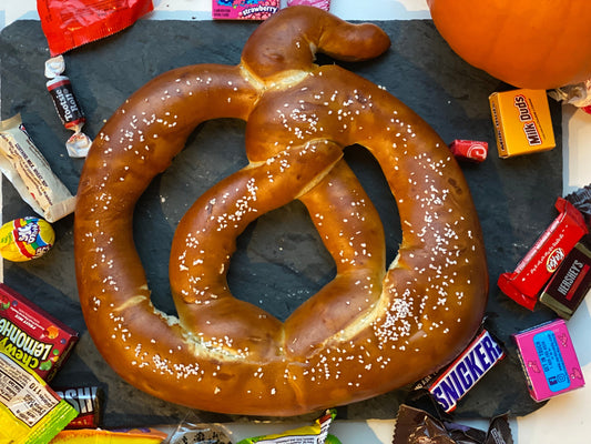 Pretzel twist in the shape of a pumpkin next to Halloween candy.